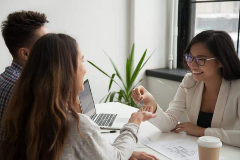 female real estate agent giving keys excited couple